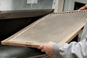 A person replacing a furnace filter
