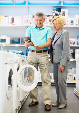 A couple in a store standing in front of washers and dryers