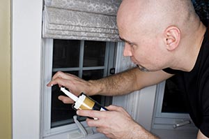 A person caulking around a window