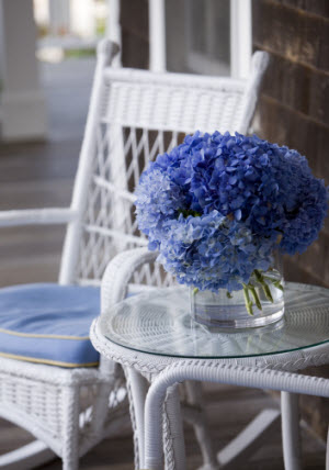 Patio area with white wicker furniture and blue hydrangeas