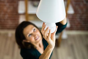 A woman changing to an LED light bulb in fixture