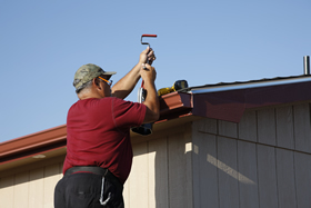 A mobile home owner caulking a gutter